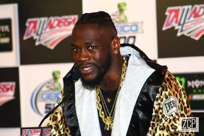 Deontay Wilder sitting at a press conference and looking at the camera