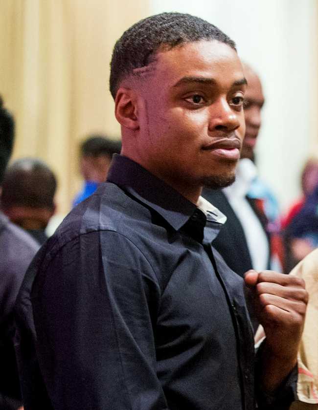 Errol Spence looking off to the right of the camera, holding his fist up as he poses for the picture