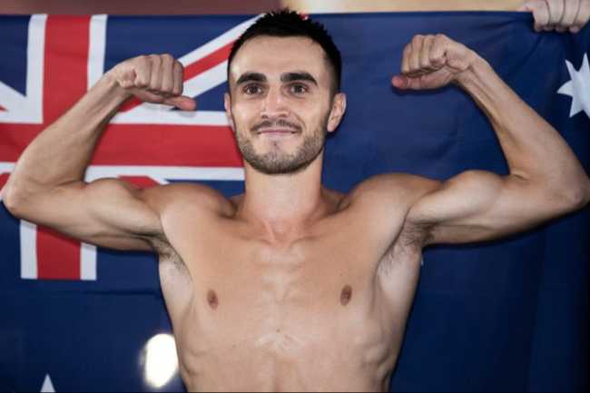 Andrew Moloney topless doing a muscle pose